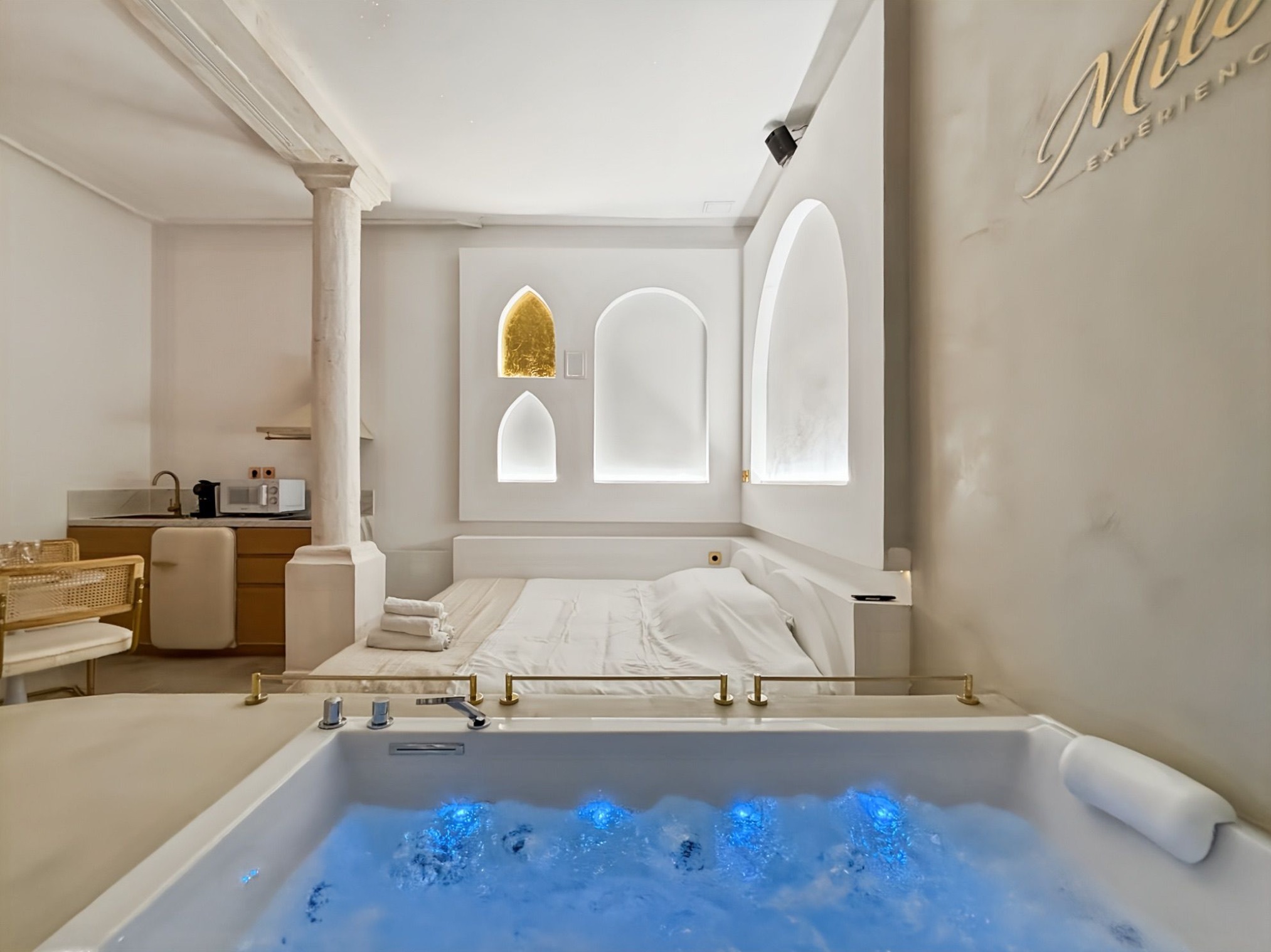 Jacuzzi illuminé de bleu face au lit dans la Balnéo Room