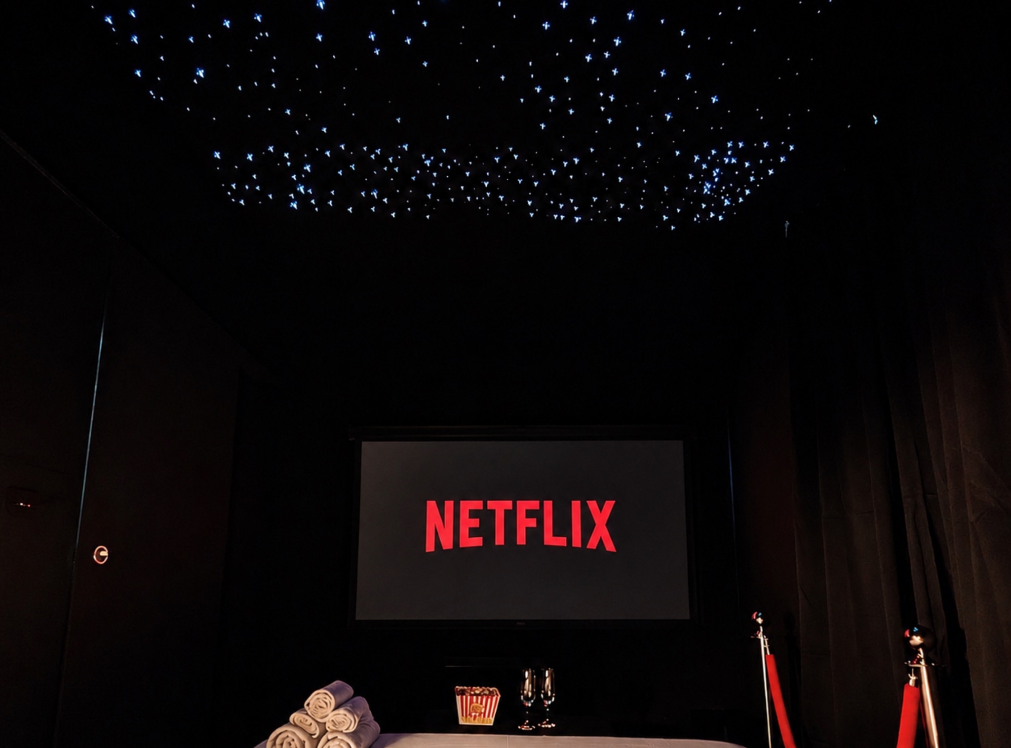 Ciné Room à Tarbes : salle de projection privée avec écran 4K, plafond étoilé et cordons rouges