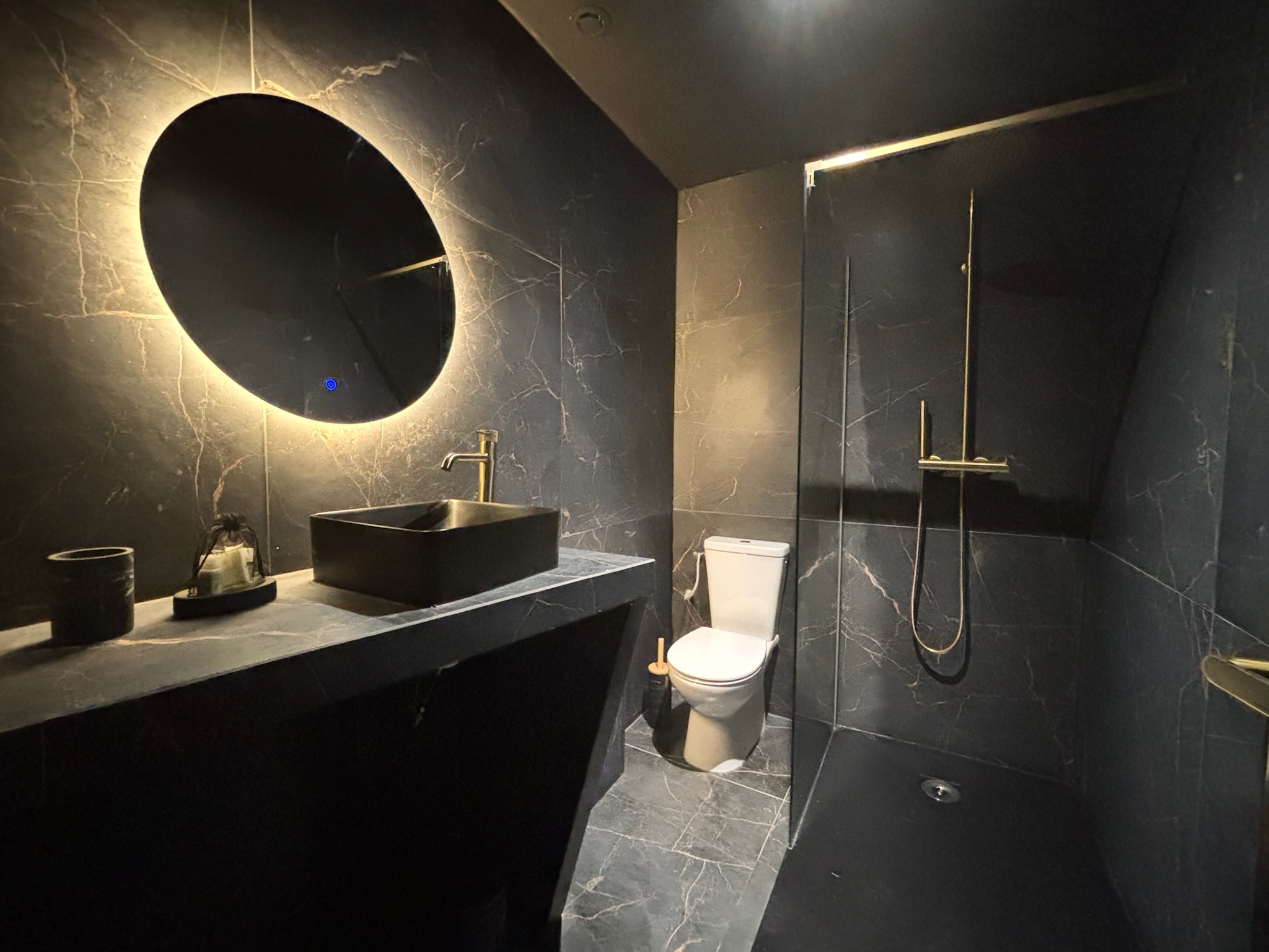Salle de bain noire et dorée de la Ciné Room à Tarbes